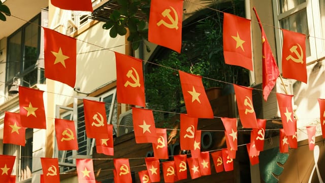 Red flags with communist symbols and yellow stars hanging in a city street.