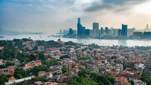 Scenic aerial view of Xiamen city skyscrapers and residential districts with lush greenery and waterways.
