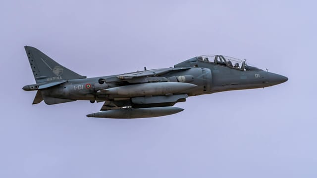 A military jet aircraft flying through a clear blue sky during daytime.