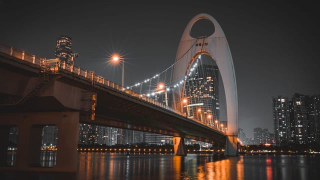 Stunning night view of Liede Bridge over Pearl River in Guangzhou with modern architecture and city lights.