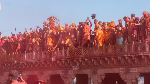 Crowds celebrate Holi with vibrant colors at Nandgaon temple in India.