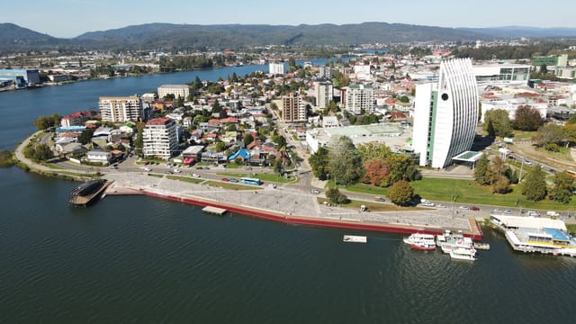 Aerial photo of Valdivia's waterfront showcasing buildings, rivers, and landscapes.