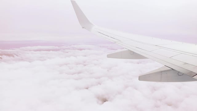 A serene view of an airplane wing cruising above the clouds, showcasing the beauty of aerial travel.