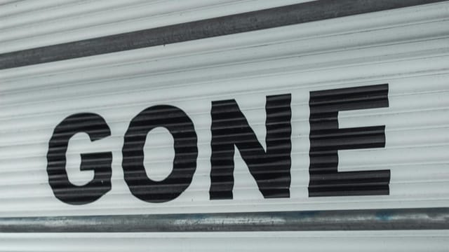 Close-up of a corrugated steel shutter with bold black 'Gone' text, providing a minimalist industrial vibe.