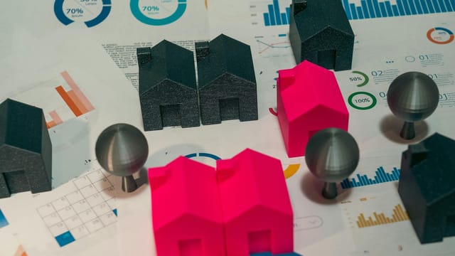 Abstract representation of real estate market analysis with model houses and charts.