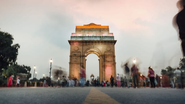 A stunning view of India Gate in New Delhi at sunset with a dynamic crowd.