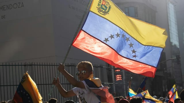 A young boy waves the Venezuelan flag during a vibrant street protest.