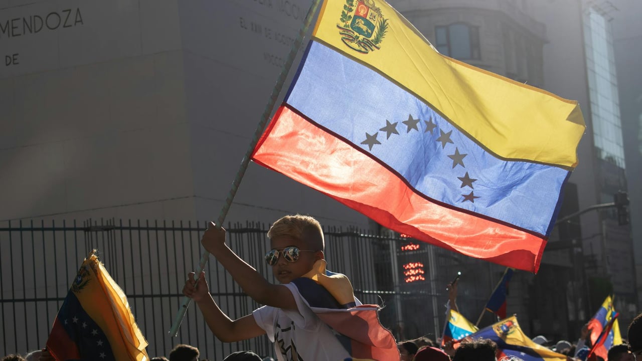A young boy waves the Venezuelan flag during a vibrant street protest.