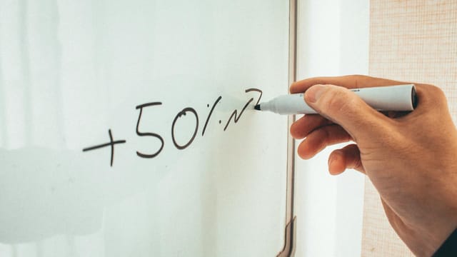 Crop anonymous male teacher writing math formulas on whiteboard during lessons in modern classroom