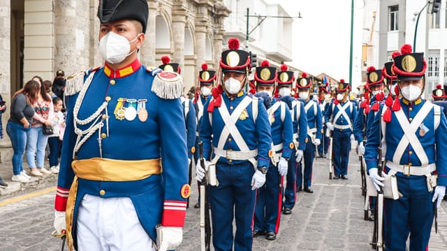A group of uniformed soldiers in ceremonial attire march during a parade in Ecuador.
