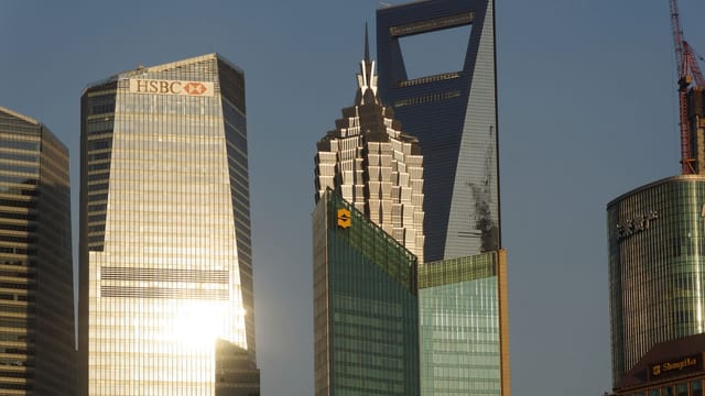 Glowing skyscrapers in Shanghai's financial district reflecting evening light.
