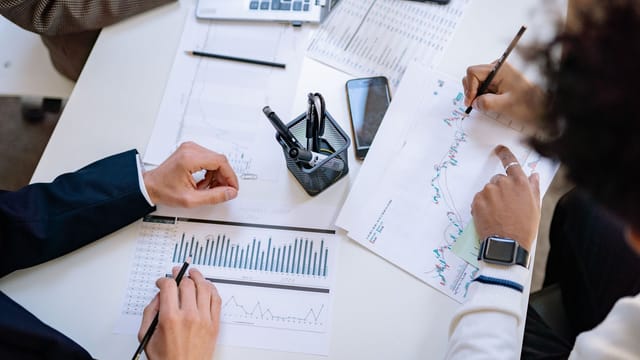 Business team analyzing financial charts and graphs during a collaborative meeting.