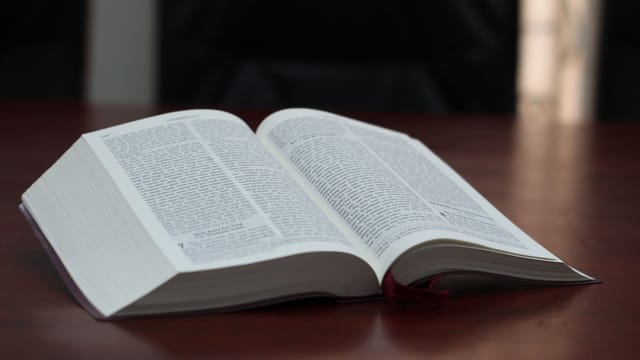 An open Bible on a wooden table, showcasing text and pages.