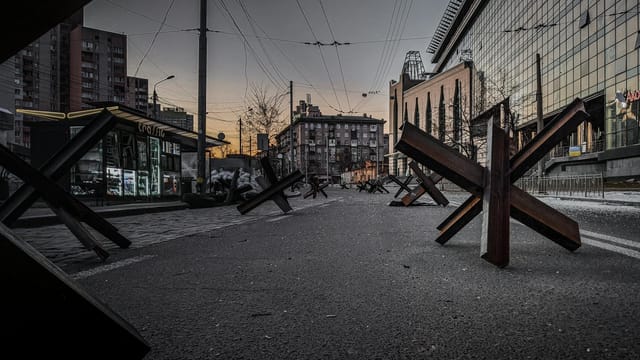 Urban street in Kyiv with anti-tank barriers at dusk, symbolizing resilience and defense.