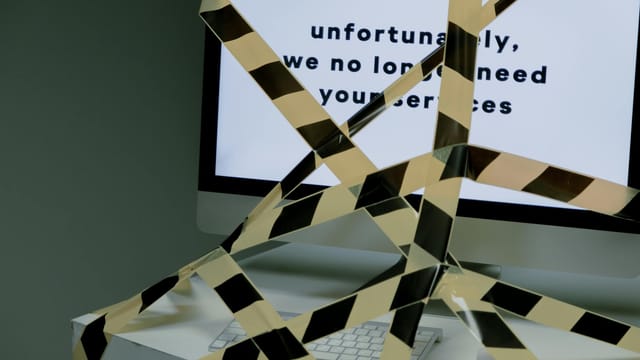A computer screen taped and displaying a termination message, symbolizing unemployment.