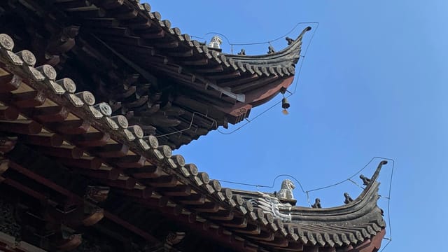 Close-up of ornate traditional Chinese temple rooftops against a clear blue sky in Tai Zhou Shi, China.