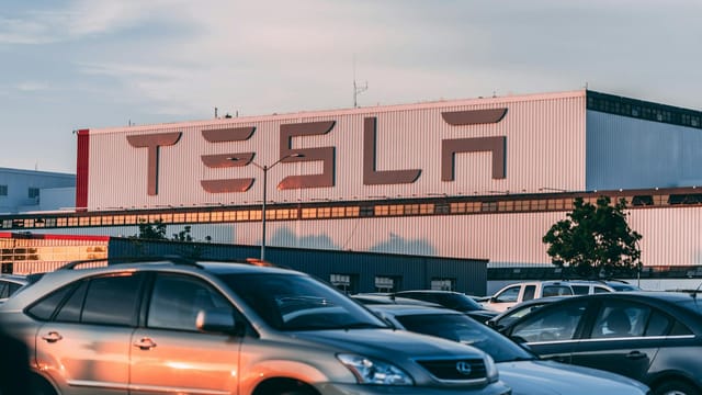 Tesla factory with parked cars during sunset, showcasing modern automotive industry vibes.