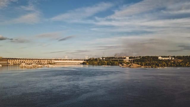 Scenic view of the Zaporizhzhia hydroelectric station on the Dnieper River under a bright blue sky.