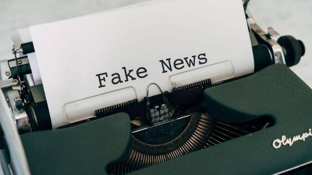 Close-up of vintage typewriter printing 'Fake News', depicting false information concepts.