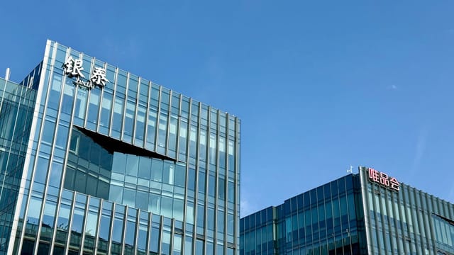 Close-up of modern glass facade buildings under a clear blue sky in Shanghai, China.
