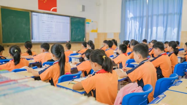 Children attentively listening in a classroom setting, showcasing focused learning in a school environment.