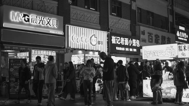 Black and white photo capturing the bustling night scene at a Nanjing street market.