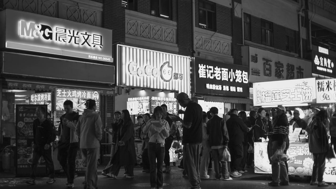 Black and white photo capturing the bustling night scene at a Nanjing street market.