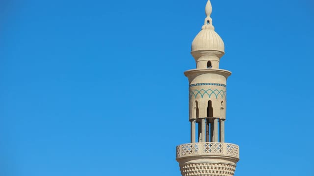 A detailed view of a traditional mosque minaret in Khaf, Iran, under a clear blue sky.