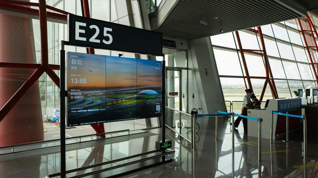 A view of a modern airport terminal showcasing Gate E25 with a flight display board.
