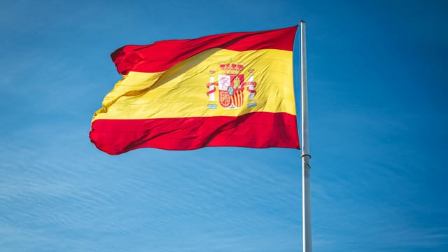 Vibrant Spanish flag waving proudly against a clear blue sky, symbolizing national pride.