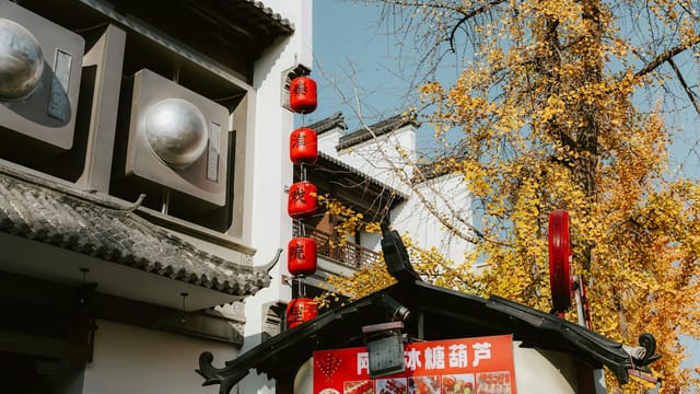 Authentic autumn street scene in Nanjing, China with vibrant red lanterns and yellow ginkgo leaves.