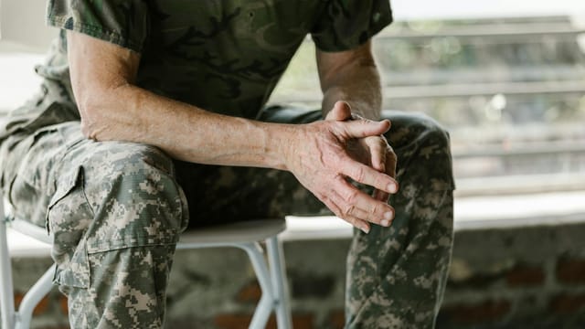 Close-up of a military veteran's hands in a therapy session, emphasizing mental health support.