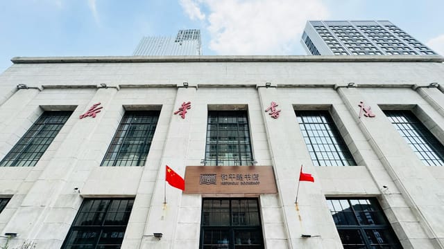 Contemporary building with Chinese flags and inscriptions in Tianjin on a sunny day.