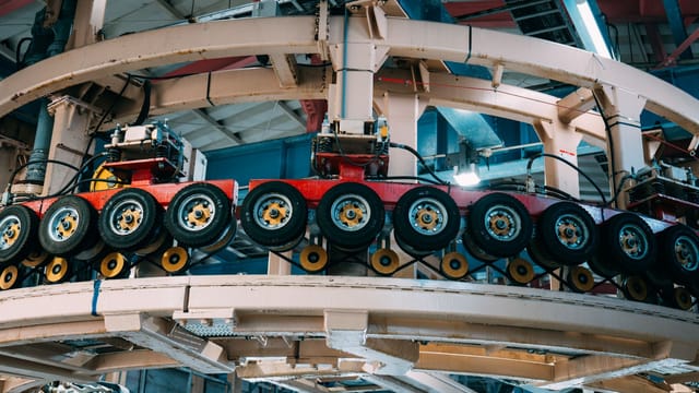 Illustrative image: Close-up view of a complex industrial conveyor system inside a manufacturing facility.