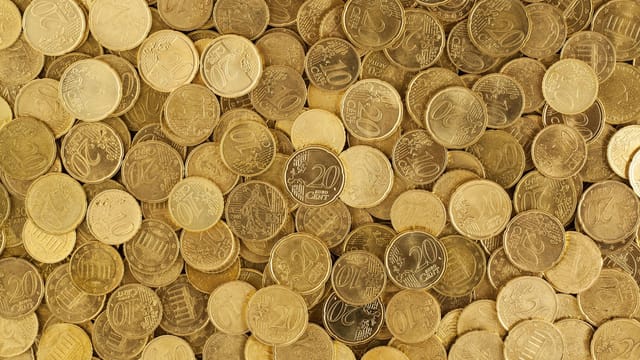 A close-up shot of Euro coins scattered in a pile, showcasing a rich golden texture.