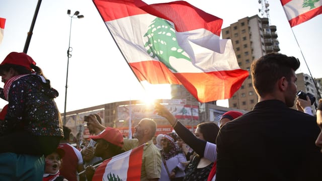 A vibrant rally in Tripoli, Lebanon, showcasing patriotism with waving national flags at sunset.