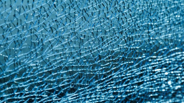 Detailed view of cracked blue glass texture with intricate patterns.