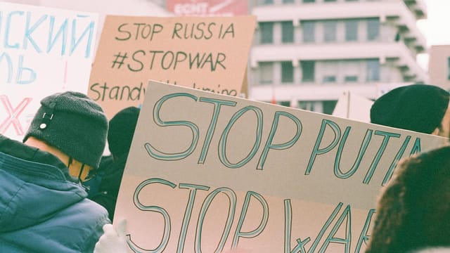 Protest signs at a rally expressing anti-war and anti-Putin sentiments.