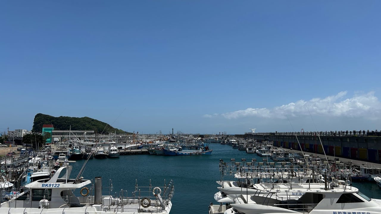 Bright summer day at Nanfang'ao Fishing Harbor with moored boats and clear blue sky.