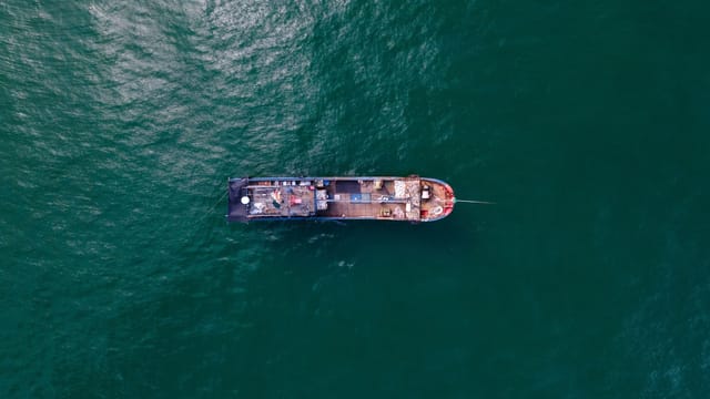 Aerial shot of a cargo ship sailing in Shantou, China, showcasing maritime transportation.