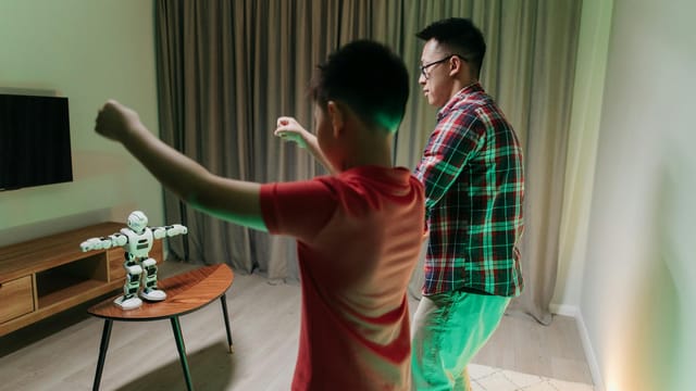 Father and son bonding by dancing with a robotic companion in their living room.