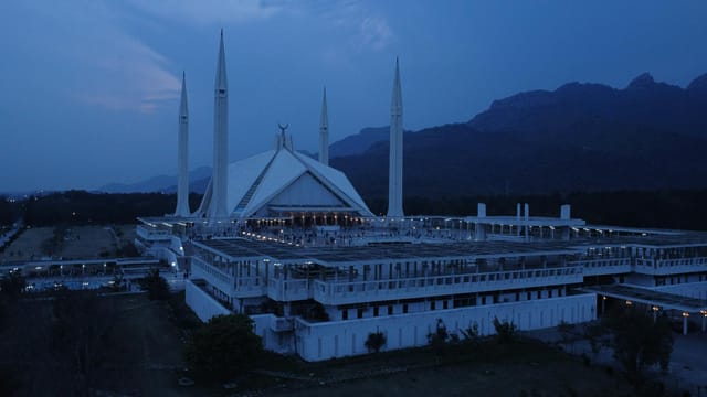 Aerial view of Faisal Mosque in Islamabad during evening twilight, showcasing its iconic minarets.