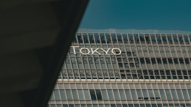 A view of a modern building in Tokyo with reflective glass and urban architecture.