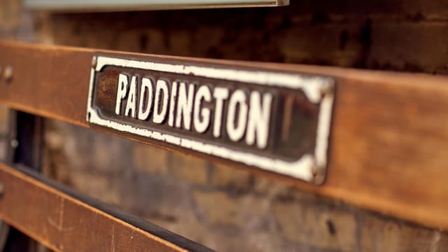 Close-up of a vintage Paddington station sign with a rustic and sepia tone.