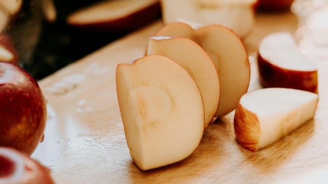 Close-up of fresh apple slices on a wooden cutting board, showcasing healthy snacking.