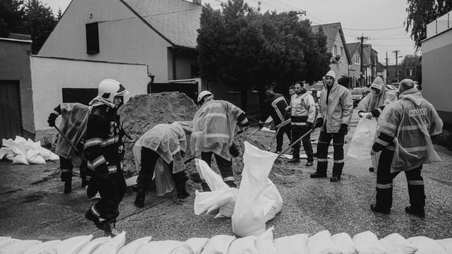 Black and white image of workers filling sandbags in flood response.