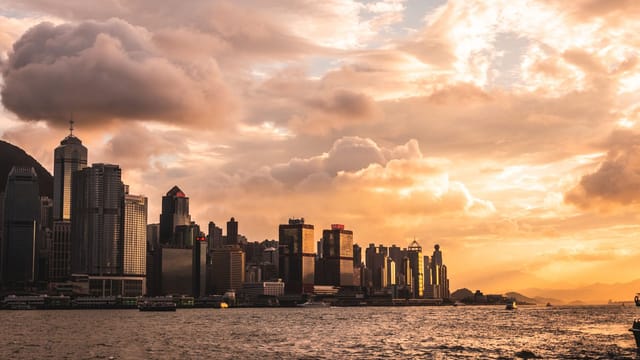 Capture of Hong Kong's skyline at sunset with dramatic clouds and waterfront view.