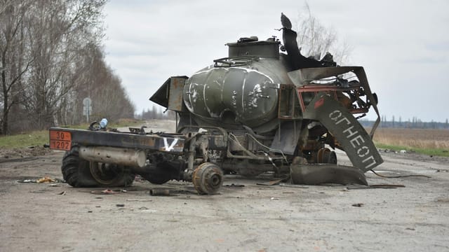 Destroyed military tank on deserted road, showcasing war impact.