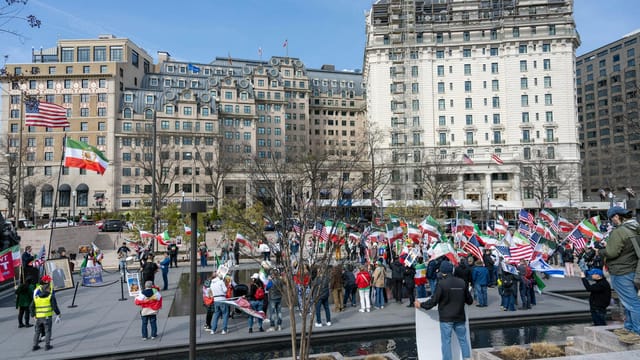 A vibrant demonstration with flags in Lafayette Square, Washington, DC with historic buildings in the background.