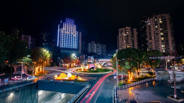 Dynamic urban night scene featuring light trails and illuminated skyscrapers.